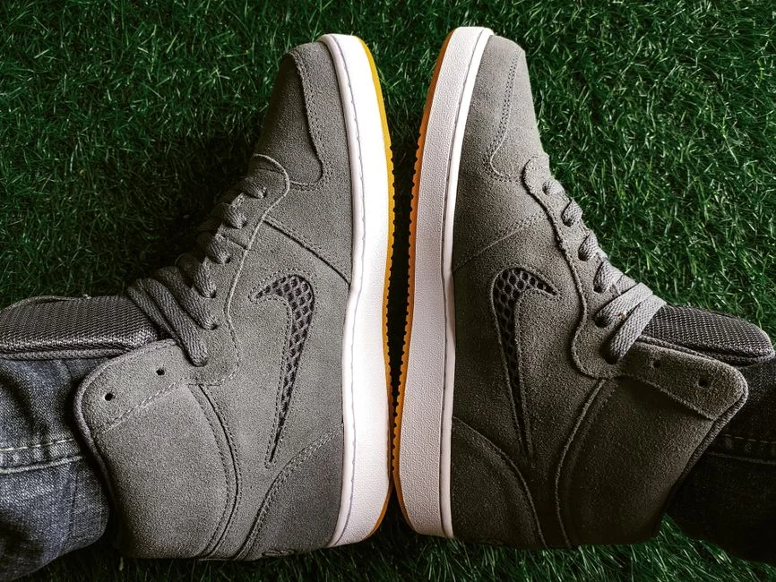 Top view of gray sneakers on green grass, perfect for fashion and outdoors imagery.