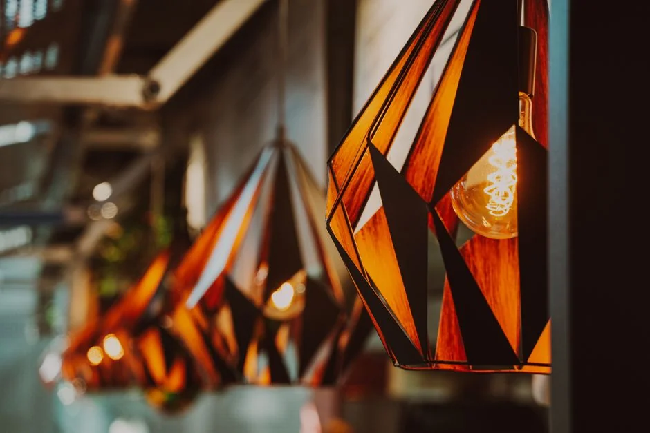 Close-up of a geometric ceiling lamp with warm glowing light in an indoor setting.