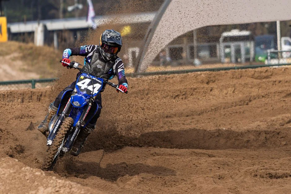 Thrilling action shot of a motocross rider navigating a dirt track, showcasing speed and skill.