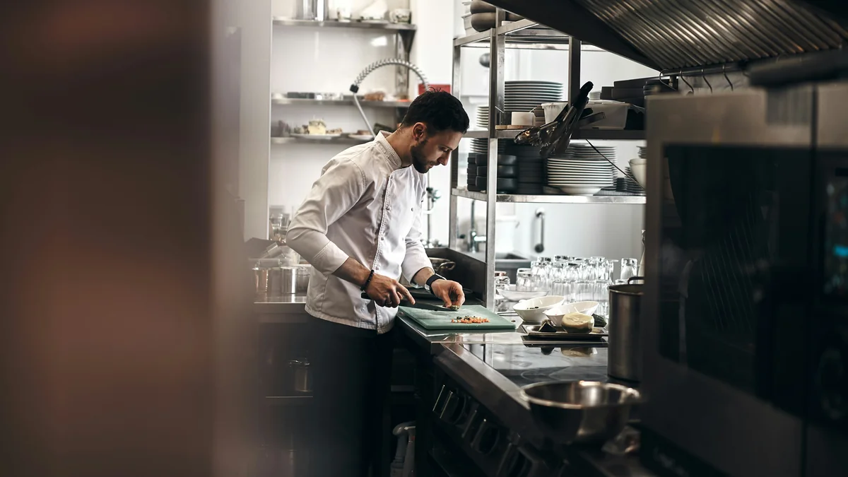 A chef dressed in a white coat working in a kitchen. @novokayn on Instagram