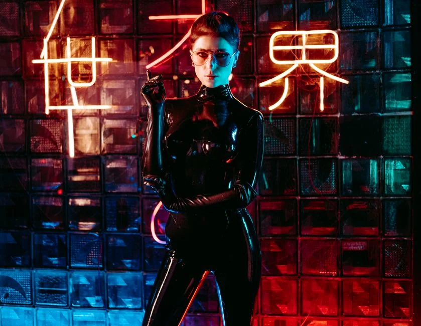 A captivating portrait of a woman in a glossy latex suit with vibrant neon lighting.